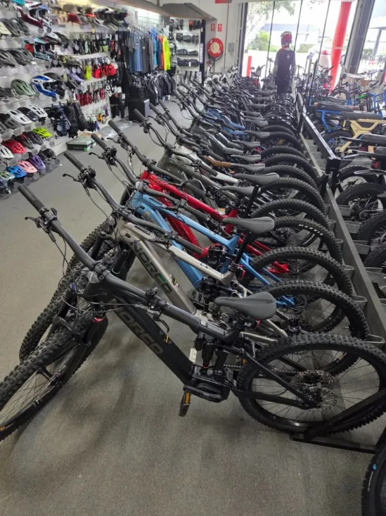 A long row of Norco and Focus electric mountain bikes on the shop floor