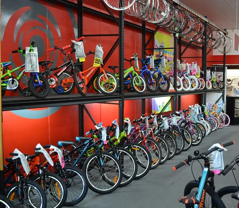 Rows of kids bikes under a red Bike Hub wall