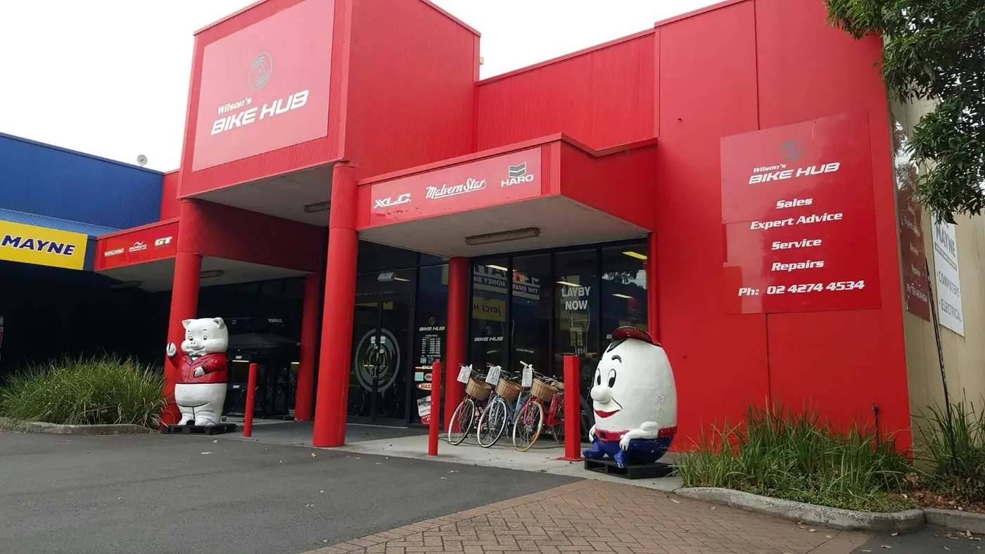 The red Wilson's Bike Hub shopfront on King Street, with Humpty and the pig statue at the door